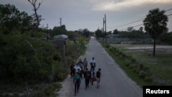 Sekelompok migran dari China berjalan melewati warga ketika akan menyerahkan diri kepada para petugas Patroli Perbatasan di Fronton, Texast. 4 April 2023. (Foto: Reuters)