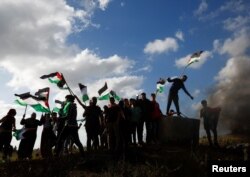 Palestinians take part in a protest against the holding of the annual flag march in Jerusalem which marks Jerusalem Day, at the Israel-Gaza border fence east of Gaza City, May 18, 2023.