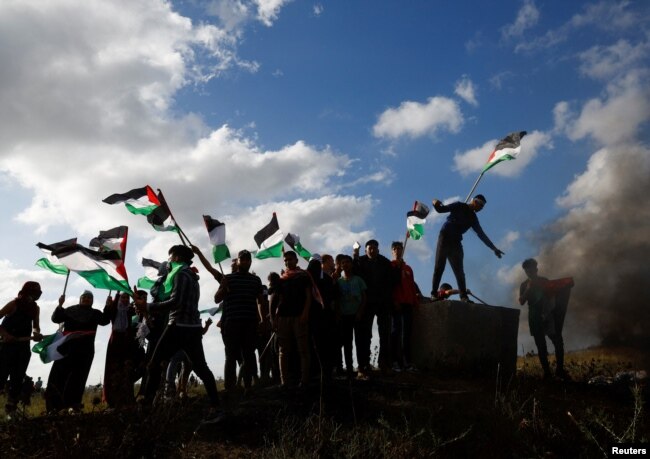 Palestinians take part in a protest against the holding of the annual flag march in Jerusalem which marks Jerusalem Day, at the Israel-Gaza border fence east of Gaza City, May 18, 2023.