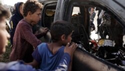 People gather around a destroyed car used by the US-based aid group World Central Kitchen, after it was hit by an Israeli strike the previous day in Deir al-Balah in the central Gaza Strip on April 2, 2024.