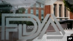 FILE - A U.S. Food and Drug Administration building is seen behind FDA logos at a bus stop on the agency's campus in Silver Spring, Md., on Aug. 2, 2018. (AP Photo/Jacquelyn Martin, File)