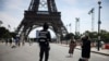 A security officer watches people taken photographs in front of the Eiffel Tower at the 2024 Summer Olympics in Paris, July 20, 2024.