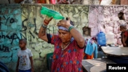 FILE - A woman pours water on her head after filling her containers with drinking water from a municipal tanker on a hot summer day in New Delhi, India, May 21, 2024.