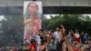 Protesters celebrate beside a defaced portrait of Prime Minister Sheikh Hasina after news of her resignation, in Dhaka, Bangladesh, Aug. 5, 2024.