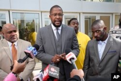 Civil lead counsel Malik Shabazz, center, speaks to reporters after the sentencing of a fourth ex-Rankin County law enforcement officer, while his client Michael Corey Jenkins, right, and co-counsel Trent Walker listen in Jackson, Miss., March 20, 2024.