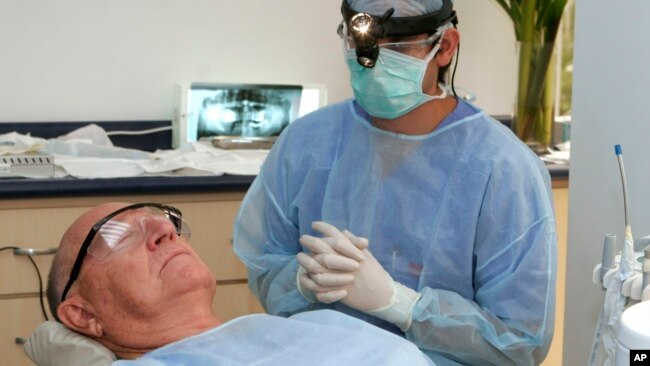 FILE - In this photo made June 26, 2009, Costa Rican Dr. Luis Obando, right, prepares to perform a root canal on Bill Jones, of Dallas, Texas at Meza Dental Care in San Jose, Costa Rica. (AP File photo)