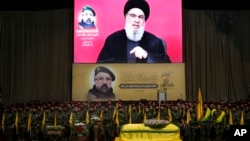 Hezbollah fighters stand behind the coffin of their top commander Fouad Shukur, who was killed by an Israeli airstrike July 30, as Hezbollah leader Sayyed Hassan Nasrallah, displayed on a screen, speaks during the funeral in a southern suburb of Beirut, Lebanon, Aug. 1, 2024.