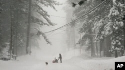 A person tries to clear snow from a road during a storm, March 2, 2024, in Truckee, Calif.