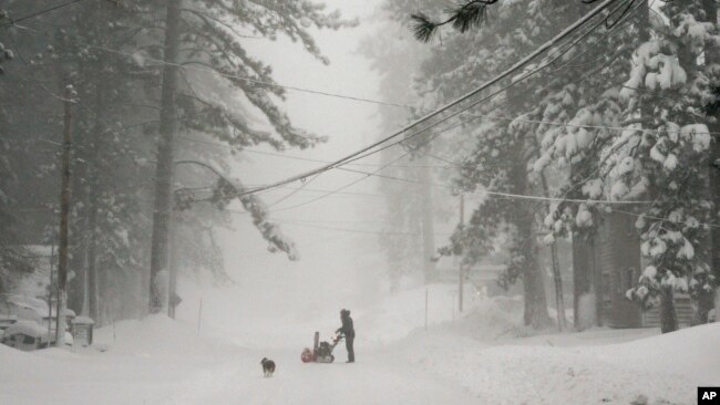 A person tries to clear snow from a road during a storm, March 2, 2024, in Truckee, Calif.