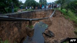 People look at a collapsed road caused by flooding due to heavy rains following Cyclone Freddy in Blantyre, Malawi, on March 13, 2023. 