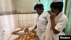 FILE - Nurses talk with a 13 year-old boy with a gunshot wound as he lies in a hospital bed in Kumba, Cameroon, Oct. 25, 2020. Due to superstitious beliefs, blood donations for transfusions in Cameroon have fallen to critically low levels.