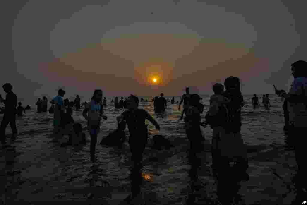 People gather at the Juhu Beach on the Arabian Sea coast as the sun sets on New Year's eve in Mumbai, India, Dec. 31, 2023.