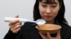 An employee of Kirin Holdings demonstrates an electric spoon in Tokyo, May 20, 2024. (REUTERS/Tom Bateman)