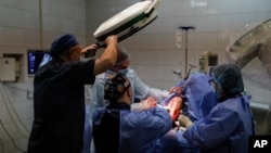 Petro Nikitin, left, takes part a surgery operation of Ukrainian serviceman at the military hospital in Kyiv, Ukraine, on Thursday, May 5, 2023. (AP Photo/Alex Babenko)