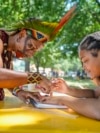 Txatxu Pataxo, left, of the Pataxo people of Bahia, Brazil, shows Eva Quiroz, 16, of Takoma Park, Maryland, how to draw a pattern traditional used in body painting, during the Smithsonian Folklife Festival in Washington, June 26, 2024.