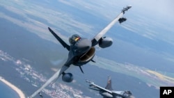 FILE - A Romanian Air Force F-16 military fighter jet, left, and a Portuguese Air Force F-16 fly over the Baltic Sea, May 22, 2023. The US has given its approval for the Netherlands to deliver F-16s to Ukraine.
