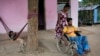 FILE - Thangarasa Kirubakaran, a former rebel fighter who was disabled in the civil war, gets help from his wife as he sits in a wheelchair outside his home in Mullaitivu, Sri Lanka, May 6, 2023. 