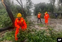 Rescue workers remove the fallen tress after a storm in Teknaf, near Cox's Bazar, Bangladesh, May 14, 2023.