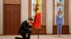 Moldova's president Maia Sandu, right, watches as Moldovan Prime Minister Dorin Recean kneels down in front of the national flag during a swearing-in ceremony in Chisinau, Feb. 16, 2023.