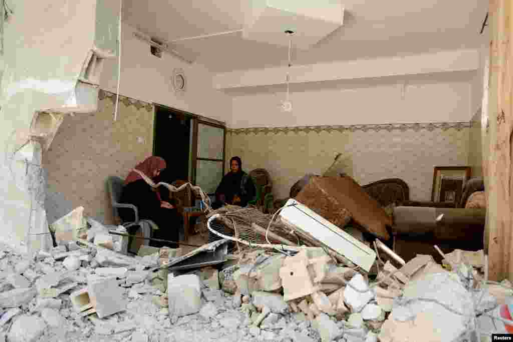 Palestinian women sit inside a damaged building in the aftermath of an Israeli raid, in Tulkarm, in the Israeli-occupied West Bank.