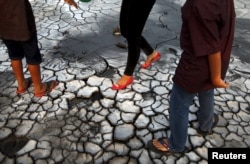 Wisatawan berjalan di atas lumpur kering di lapangan lumpur Lapindo, Sidoarjo, 11 Oktober 2015. (Foto: REUTERS/Beawiharta)