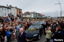 A hearse carrying the coffin of late Irish singer Sinead O'Connor passes by during her funeral procession as fans line the street to say their last goodbye to her, in Bray, Ireland, Aug. 8, 2023.