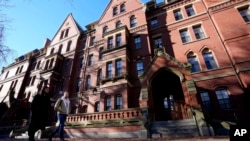 FILE - Passers-by walk on the campus of Harvard University, Dec. 12, 2023, in Cambridge, Mass.