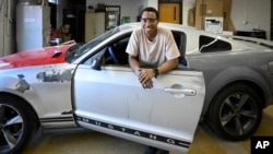 Tennessee College of Applied Technology Nashville student Robert Nivyayo poses with his car during auto collision repair class Wednesday, April 13, 2023. (AP Photo/John Amis)