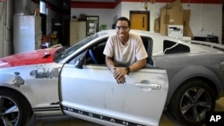 Tennessee College of Applied Technology Nashville student Robert Nivyayo poses with his car during auto collision repair class Wednesday, April 13, 2023. (AP Photo/John Amis)