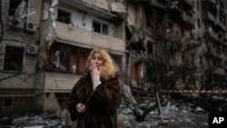 Natali Sevriukova is overcome with emotion as she stands outside her destroyed apartment building following a rocket attack in Kyiv, Ukraine, Feb. 25, 2022.