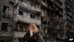 A woman is overcome with emotion as she stands outside her destroyed apartment building following a Russian rocket attack in Kyiv, Ukraine, Feb. 25, 2022.