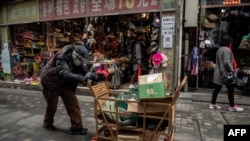 Seorang perempuan lansia mendorong gerobak berisi barang bekas yang bisa didaur ulang di sebuah jalan di Beijing, 5 Maret 2021. (Foto: Nicholas Asfouri/AFP)