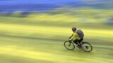 A cyclist rides on a painted road, after Protest group 'Led by Donkeys' spread paint in the colours of the Ukrainian flag on the road, outside the Russian Embassy in London, Feb. 23, 2023. 
