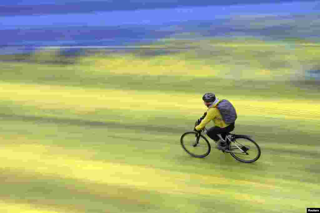 A cyclist rides on a painted road, after Protest group &#39;Led by Donkeys&#39; spread paint in the colors of the Ukrainian flag on the road, outside the Russian Embassy in London,&nbsp;ahead of the first anniversary of Russia&#39;s invasion of Ukraine.