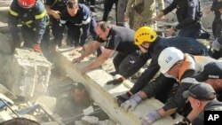 In this photo provided by the National Police of Ukraine, emergency services and policemen work to save an injured police officer from under the rubble following a Russian attack in Kryvyi Rih, Ukraine, Sept. 8, 2023. 