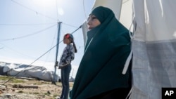 FILE - A woman sits outside a tent in Roj detention camp in northeast Syria, Feb. 9, 2022.