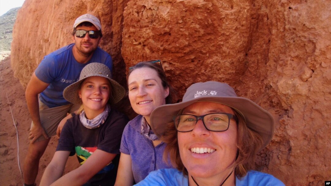 In this undated photo provided to the Associated Press by Stellenbosch University, researcher Michele Francis, right, and other researchers pose next to an ancient termite mound in Namaqualand, South Africa. 