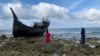 Dua orang warga Kota Sabang saat melihat kapal yang digunakan pengungsi Rohingya mengarungi lautan dan berlabuh di pesisir Le Meulee, Kota Sabang, Aceh. (Foto: VOA/Anugrah Andriansyah)