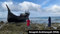 Dua orang warga Kota Sabang saat melihat kapal yang digunakan pengungsi Rohingya mengarungi lautan dan berlabuh di pesisir Le Meulee, Kota Sabang, Aceh. (Foto: VOA/Anugrah Andriansyah)