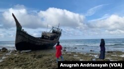 Dua orang warga Kota Sabang saat melihat kapal yang digunakan pengungsi Rohingya mengarungi lautan dan berlabuh di pesisir Le Meulee, Kota Sabang, Aceh. (Foto: VOA/Anugrah Andriansyah)