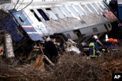 A Greek Orthodox priest stands near firefighters as they work at the scene of a collision in Tempe, about 376 kilometers north of Athens, near Larissa city, Greece, March 1, 2023.