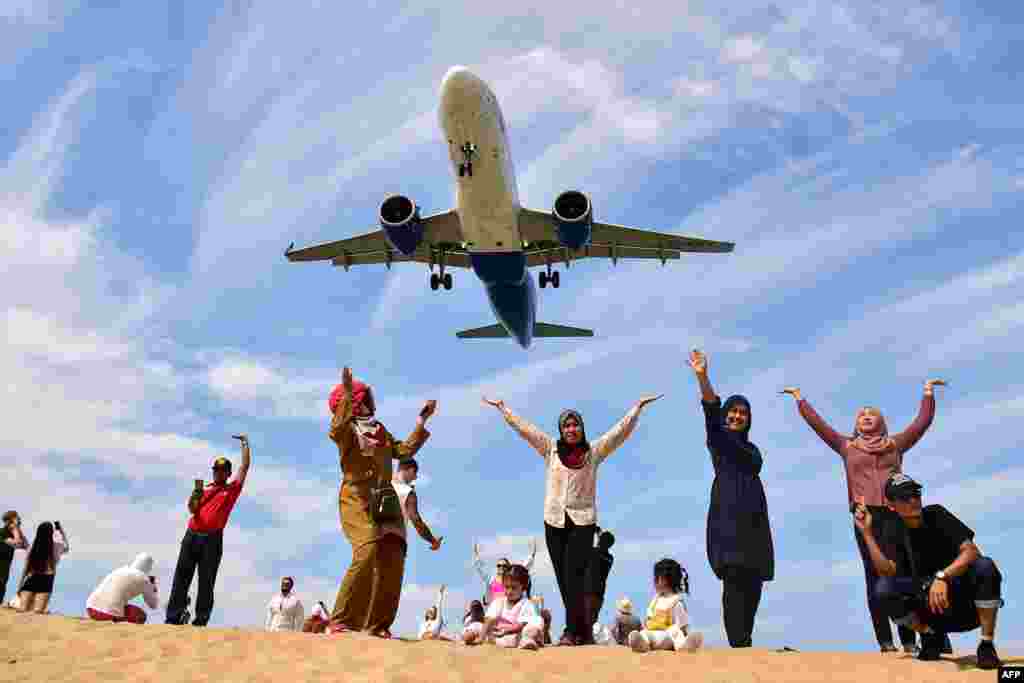 Tourists pose for picture on Mai Khao Beach as a plane lands at Phuket International Airport in Phuket province, Thailand, Feb. 13, 2023. 