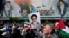 Iranians walk past a mural showing the late revolutionary founder Ayatollah Khomeini, right, Supreme Leader Ayatollah Ali Khamenei, left, as they hold Iranian and Palestinian flags in an anti-Israeli gathering in Tehran, Iran, April 19, 2024.