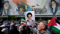 Iranians walk past a mural showing the late revolutionary founder Ayatollah Khomeini, right, Supreme Leader Ayatollah Ali Khamenei, left, as they hold Iranian and Palestinian flags in an anti-Israeli gathering in Tehran, Iran, April 19, 2024.