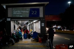 FILE - Ukrainian refugees wait in a bus stop near the border Monday, April 4, 2022, in Tijuana, Mexico.