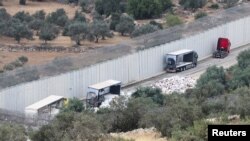 Truk-truk yang membawa bantuan ke Gaza terhenti setelah dirusak oleh para pemukim Israel dekat pos pemeriksaan tak jauh dari Hebron di Tepi Barat yang diduduki Israel, Selasa, 14 Mei 2024. (Foto: Mussa Qawasma/Reuters)