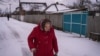 一位妇女冒雪走在乌克兰新科扎恰的街头。(2023年2月14日，美国之音博夏特拍摄)