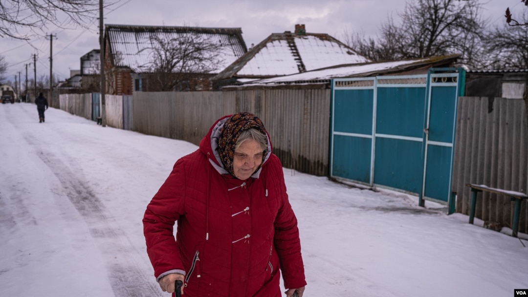 Una mujer camina sobre la nieve en Nova Kozacha, Ucrania, el 14 de febrero de 2023. Esta pequeña aldea fronteriza ha perdido más del 75 % de su población desde el comienzo de la guerra. Pocas personas han regresado, muchos temen que Rusia vuelva a atacar. [Foto: Yan Boechat, VOA]