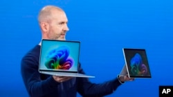 Brett Ostrum, Microsoft corporate vice president of Surface, holds up the new Surface Laptop and Surface Pro with built-in AI at an event of the company's AI assistant, Copilot, Monday, May 20, 2024, in Redmond, Wash. (AP Photo/Lindsey Wasson)