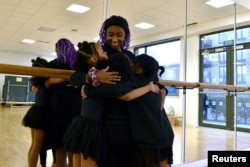 Maya, 10, Kioni, 10, Keturah, 8, and Dior, 10, hug Ruth Essel, 30, founder of Pointe Black Ballet School, at the end of class in south London, Britain, January 21, 2023. (REUTERS/Alishia Abodunde)